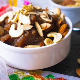 Closeup of halwa kept in a white bowl with nuts beside it