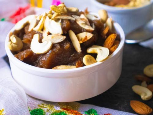 Closeup of halwa kept in a white bowl with nuts beside it