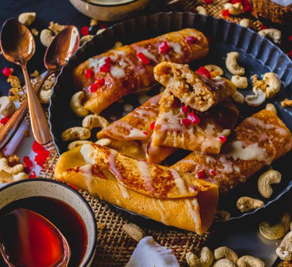 Gurer Patishapta with Coconut Filling in a black plate with gur kept beside